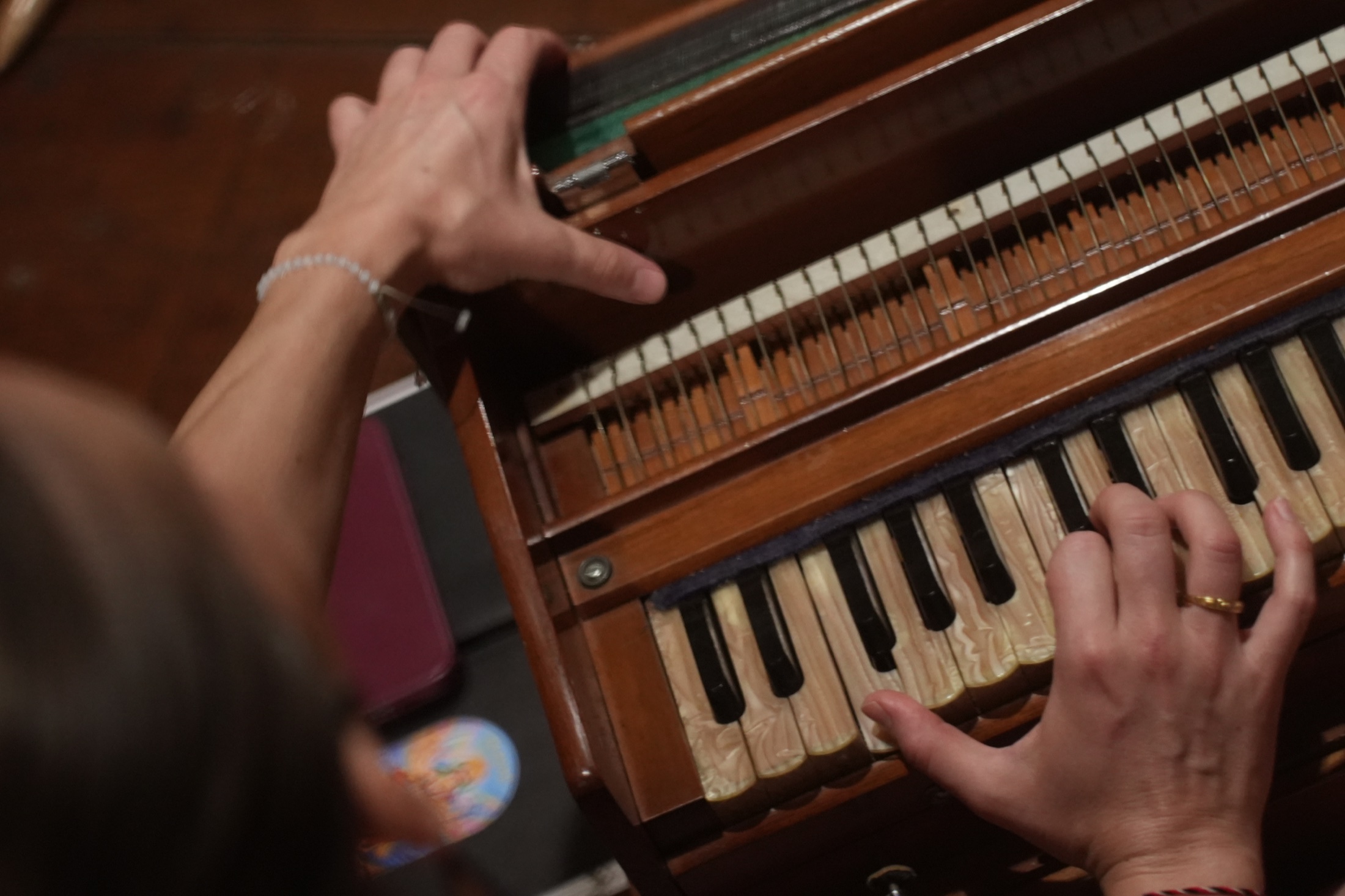 Hands playing a harmonium during a shared musical practice