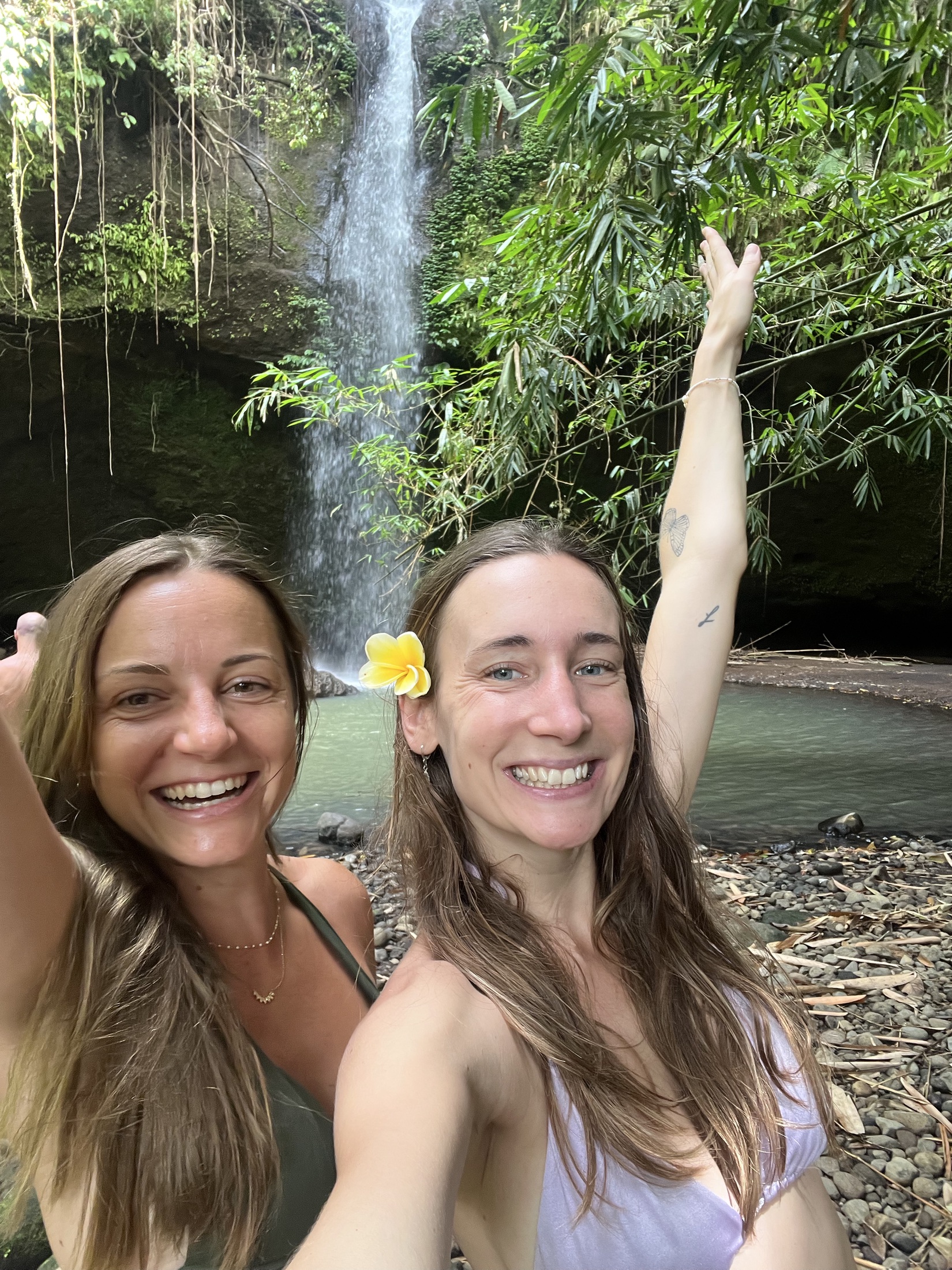 Two participants sharing a joyful moment beside a waterfall in West Bali